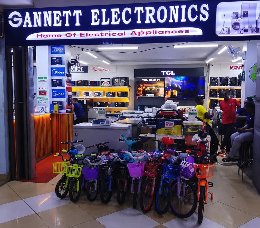 The Gannett Electronics storefront at Acacia Plaza, Kisii, with a lit sign reading Home of Electrical Appliances and kids' bicycles parked at the entrance